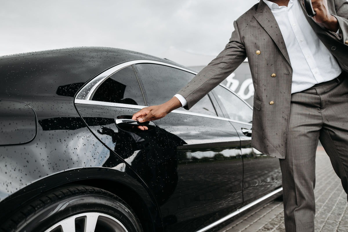 Hand opening the door of a black executive sedan
